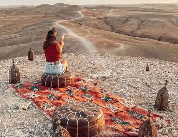 Chic picnic in the Agafay desert canyon with Moroccan rug and poufs at sunset